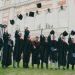 a group of people in graduation gowns holding their caps up