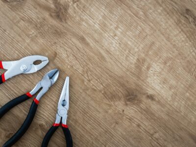 three black handled pliers on brown surface