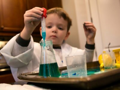 boy in white long sleeve shirt holding red and clear plastic tool