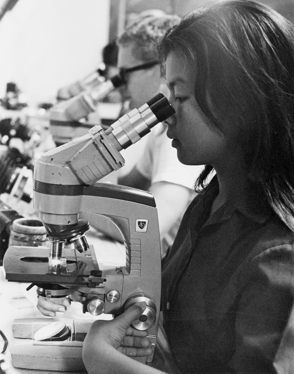 Young woman looking through a microscope in a lab.